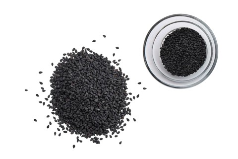 Top view of black sesame seeds in a little bowl and spilled on white background