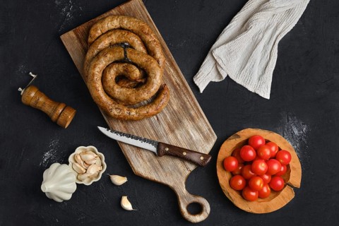 Horse meat sausage with garlic rolled on wooden cutting board