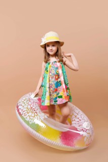 Cute child in sundress and straw hat with swimming ring playing in studio