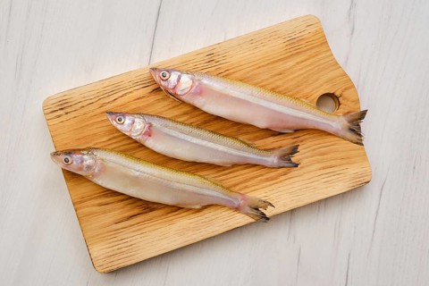 Top view of raw fresh smelt fish on wooden cutting board