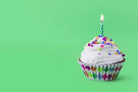 Close up delicious cupcake with burning candle green background