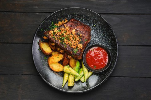 Top view of juicy grilled pork ribs with potato wedges and cucumber