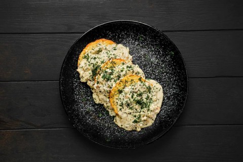 Top view of potato patty with fried boletus and creamy sauce on a plate