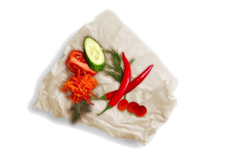Colorful vegetables on crumpled parchment for baking isolated on white. Ingredients for salad
