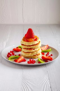 Stack of hot flapjacks served with fresh strawberries and kiwi