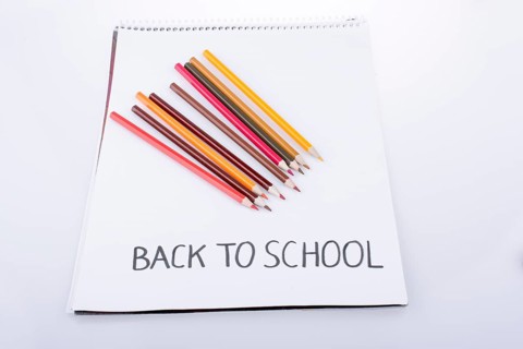 Color pencils and back to school title on a notebook