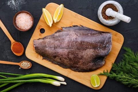 Top view of raw fresh halibut without head on wooden cutting board