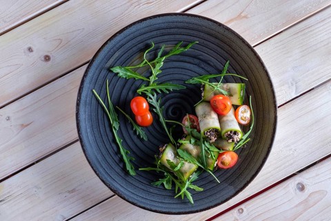 Chopped smoked salmon and black olives rolled in cucumber decorated with tomato and arugula