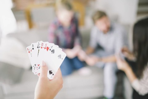 Crop person with cards playing with friends