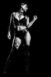 Woman with black hair and tattos in vinyl and latex outfit
