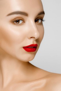 Pretty young fashion model with tan skin and red mat lips. Beauty shoot