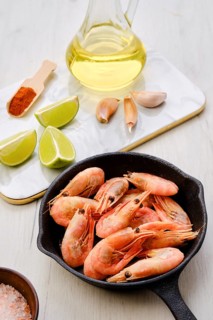 Cast iron skillet with steamed unpeeled shrimps with spice