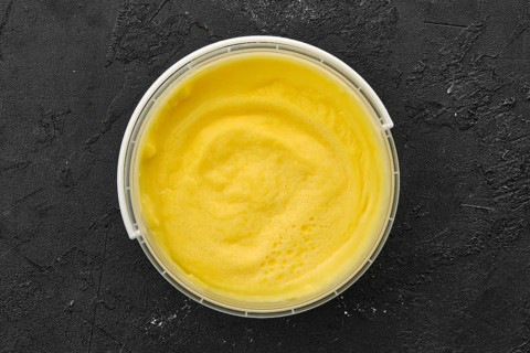 Top view of homemade cream cheese in plastic bowl