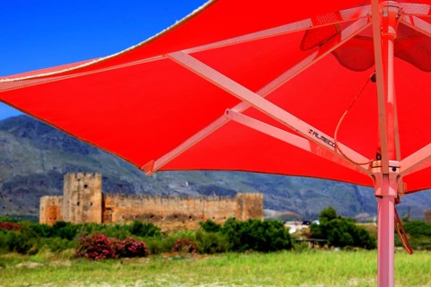 Red parasol and the fortress of Frangokastello on the south coast of the Mediterranean island