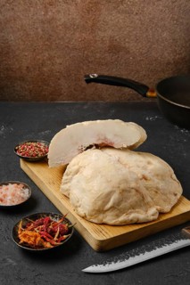 Cut lamb fat tail on kitchen table with salt and pepper