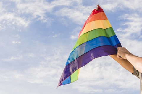 Man with big flag lgbt colors blue sky