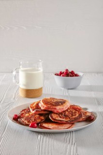 Pancakes with cherry and glass of milk on white kitchen table
