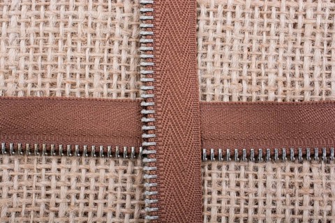 Parts of the brown color zipper on linen canvas background