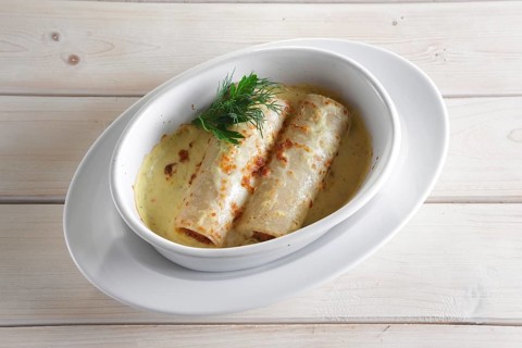 Thin pancakes with stuffing baked in oven with melted cheese