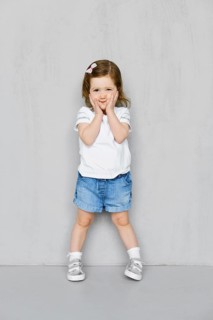 Two years old girl in white t-short and jeans shorts posing in studio