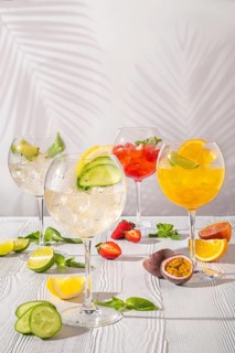 Assortment of cold lemonades in wine glasses on white wooden table in morning sunlight