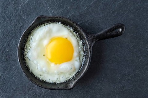 Top view of fried egg in small cast-iron skillet. Making scrambled eggs