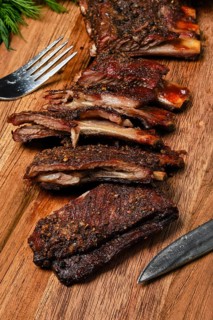 Top view of grilled lamb breast ribs on wooden cutting board