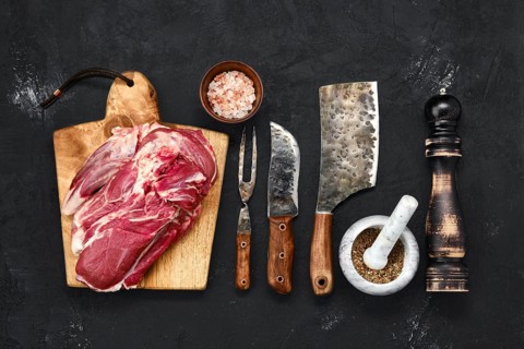 Overhead view of raw lamb shoulder without bone on wooden cutting board