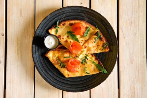 Top view of thin pancakes with salmon and sour cream