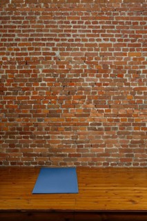 Gym mat on wooden podium with brick wall on background