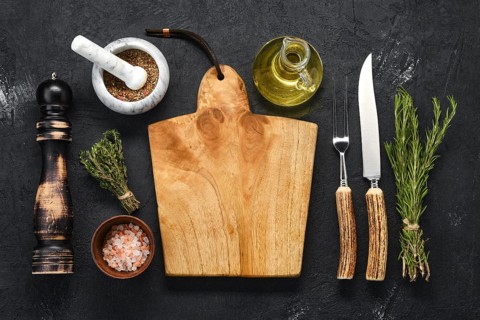 Overhead view of empty wooden cutting board with spice for steak and knife and fork with horn handle