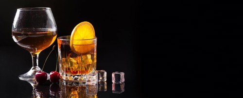 Front view whiskey with orange cognac glass with copy space