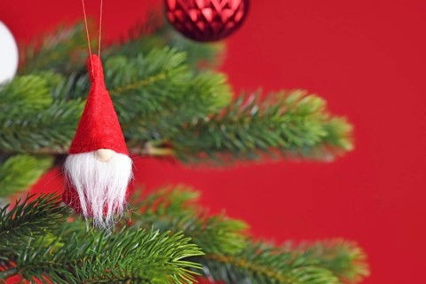 Decorated Christmas tree with cute Christmas gnome tree ornament on red background