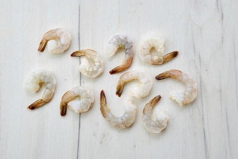 Peeled fresh raw white prawns on wooden background