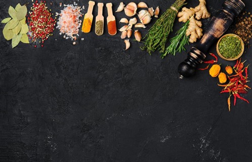 Assortment of spice and seasonings scattered on dark background