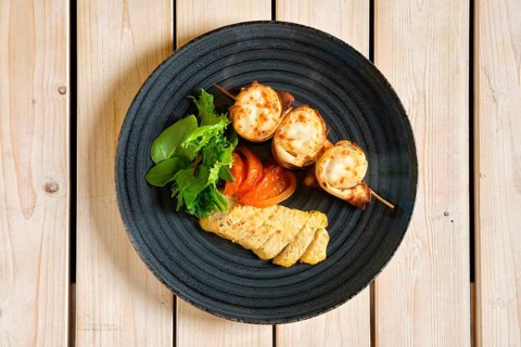 Top view of thin pancakes stuffed with soft cheese rolled and put on skewer