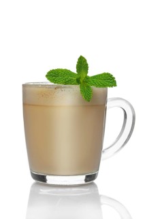 Transparent cup of cappuccino with mint liquor isolated on white