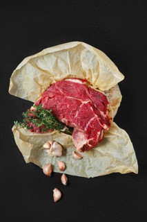 Overhead view of raw beef neck packed in wrapping paper