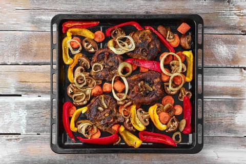 Lamb neck with champignon and vegetables baked in oven on wooden table