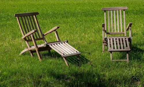 Two teak deck chairs in a meadow