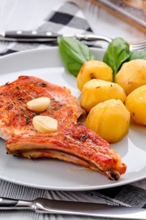 Steak with bone and potato baked in oven in a roasting pan with garlic and thyme