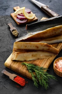 Raw fresh frozen herring carcass with spices on cutting board