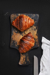 Top view of crispy croissant on wooden serving board
