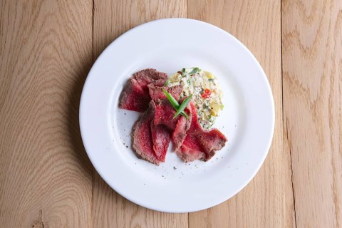 Top view of roasted meat with salad olivier on wooden table