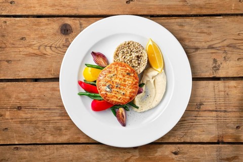 Top view of salmon cutlet with roasted vegetables and green buckwheat