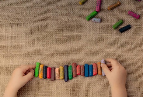 Toddlers hand putting crayons in line on canvas