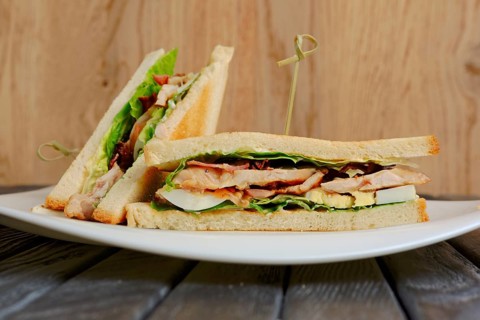 Plate with club sandwich on wooden table