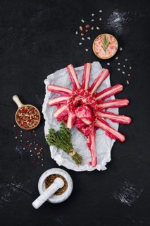Fresh raw rack of lamb on wrapping paper with herbs and seasoning