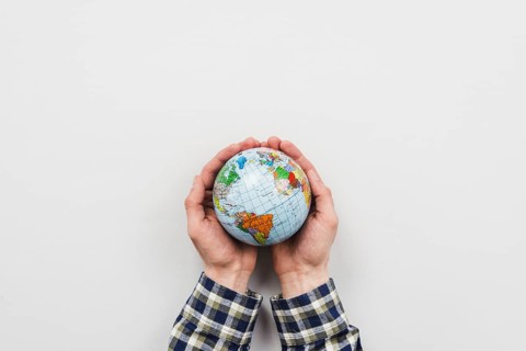Earth globe hands grey background