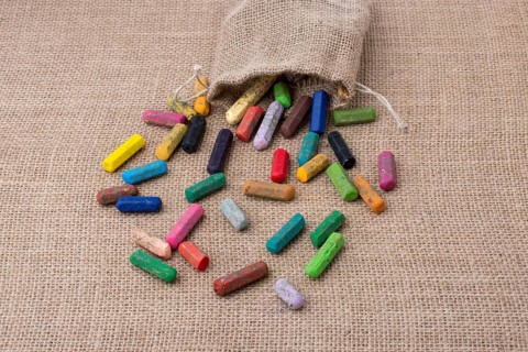 Crayons of various color out of a sack on a canvas
